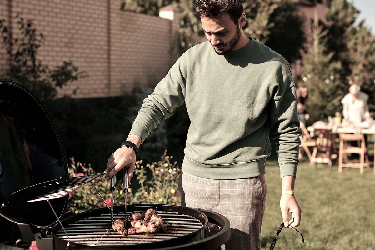 En man som grillar på en klotgrill